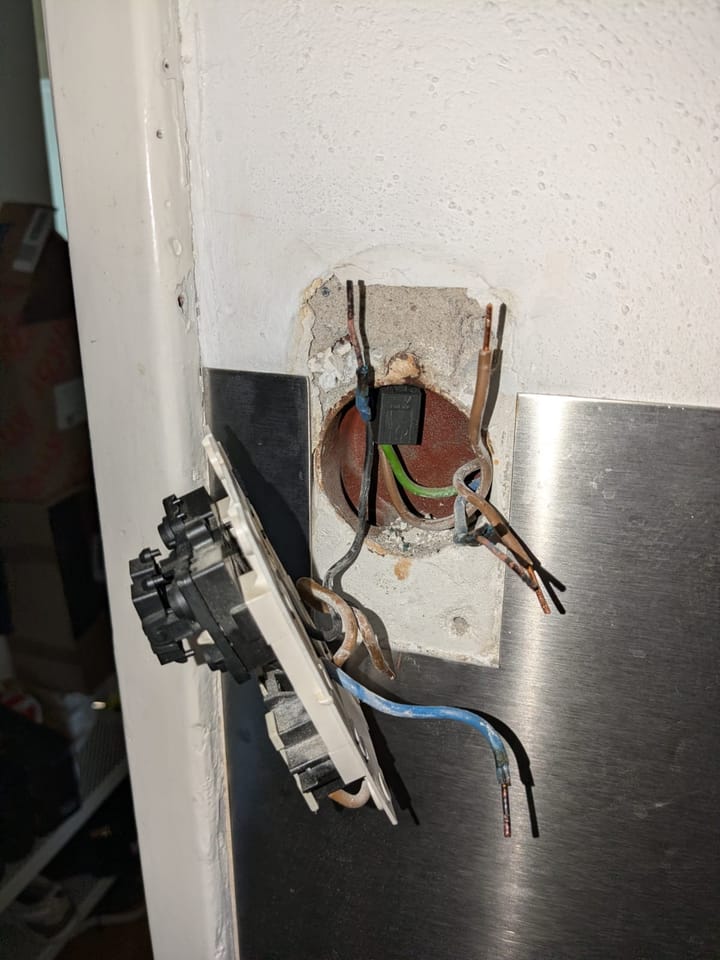 Doorgebrande draden achter een stopcontact waarop een wasmachine en vaatwasser via een stekkerdoos waren aangesloten